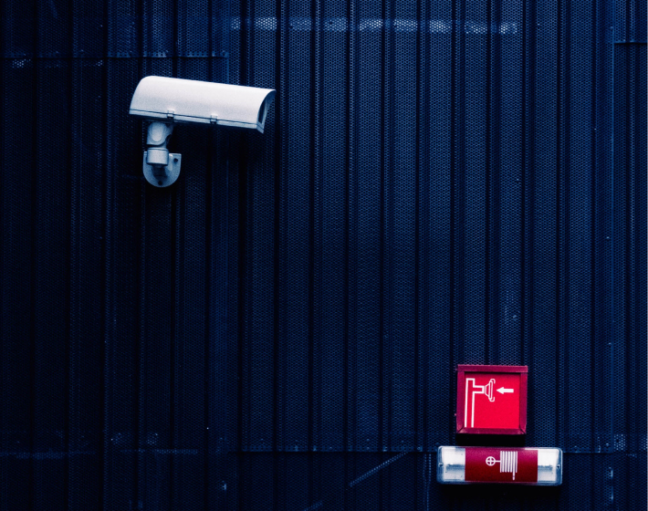 white surveillance camera on side of blue wall